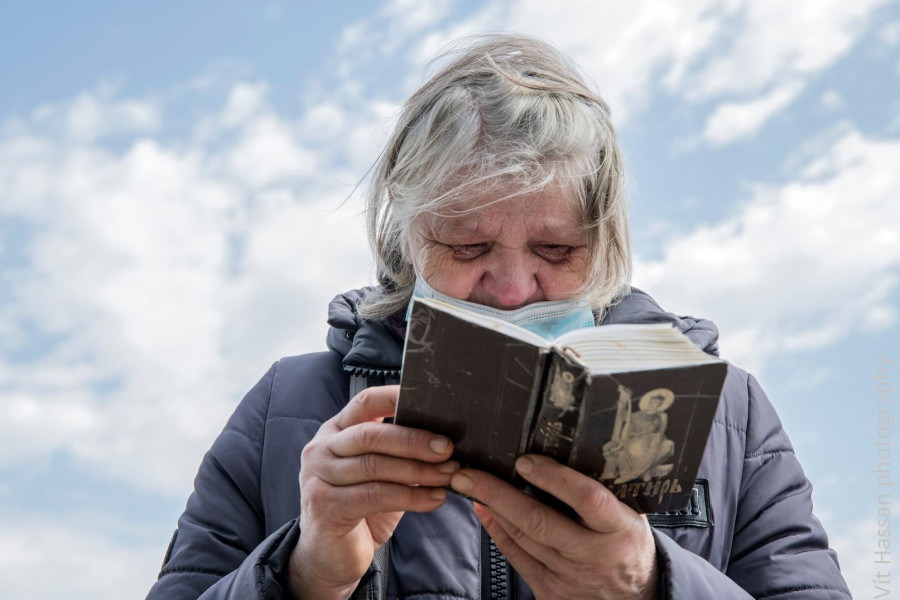 Plačící stará žena čte bibli, Pieta k uctění památky tragédie z roku 2014 v domě Odborů v Oděse.  2.5.2021, Oděsa, Ukrajina. 